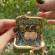 A charming little jewelry pouch designed to keep your favorite treasures safe and beautifully tucked away.

With its vintage-inspired silhouette, textured exterior, and antique-style gold-tone clasp, this compact pouch is perfect for storing your earrings and other small jewelry pieces at home or while traveling. The soft floral lining adds an unexpected touch of color and whimsy inside.