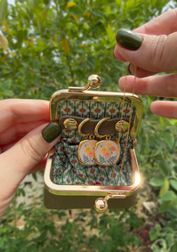 A charming little jewelry pouch designed to keep your favorite treasures safe and beautifully tucked away.

With its vintage-inspired silhouette, textured exterior, and antique-style gold-tone clasp, this compact pouch is perfect for storing your earrings and other small jewelry pieces at home or while traveling. The soft floral lining adds an unexpected touch of color and whimsy inside.